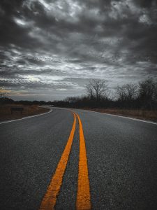 A long winding road with clouds above, a view of the road back to Texas